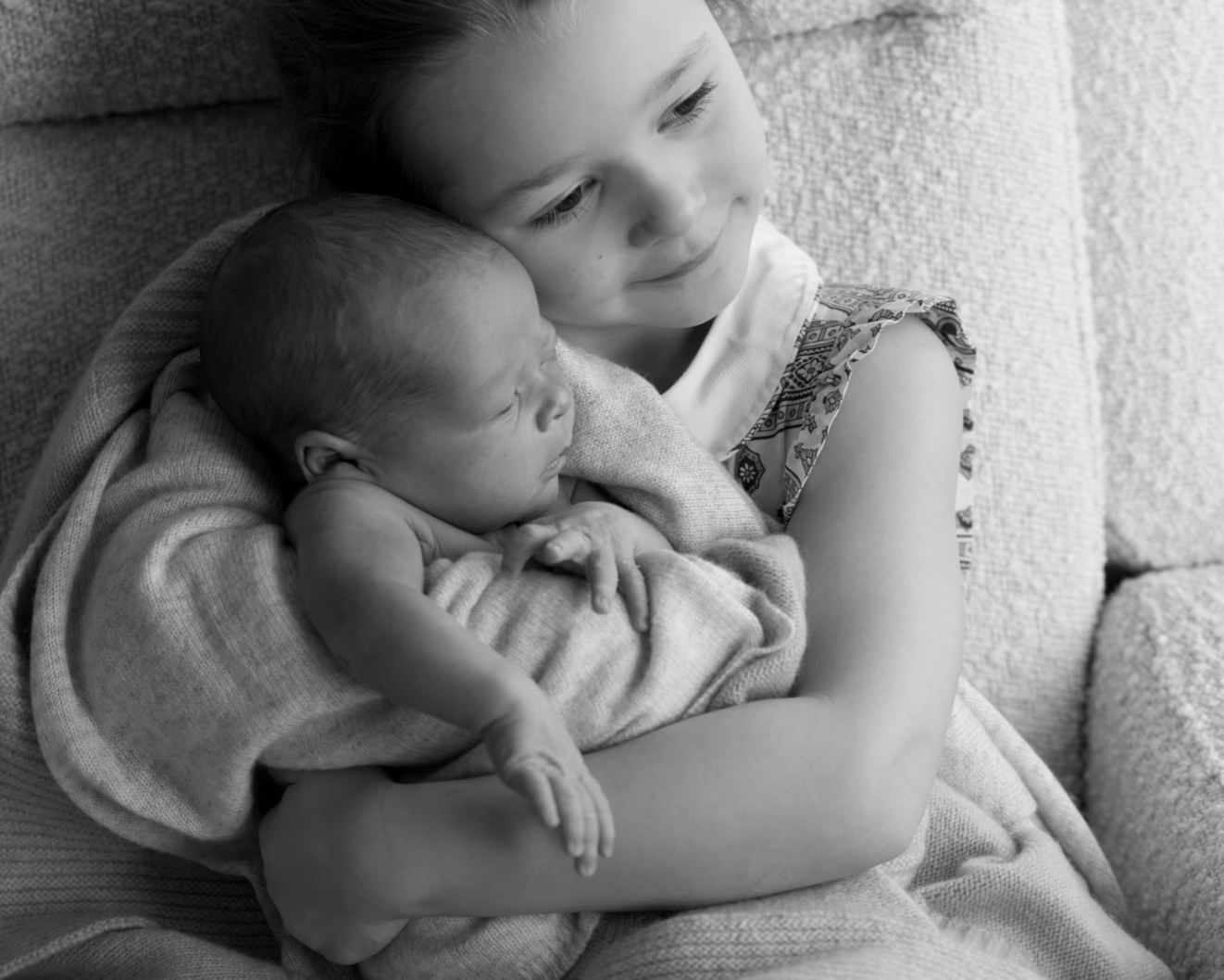 Child and sister holding a sleeping baby.